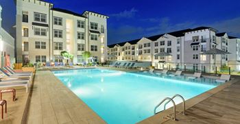 A swimming pool in front of an apartment building at night
